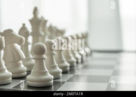 Scacchi bianchi in fila sul tabellone con vista prospettica sfocata. Concetto di giochi intellettuali e attività per il tempo libero Foto Stock