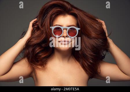 Ritratto di giovane bella donna con capelli rossi e capelli perfetti isolato su sfondo grigio scuro. Volume dei capelli Mega Foto Stock