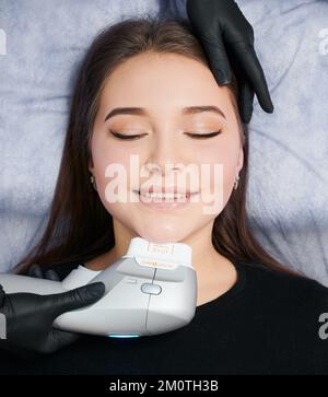 Kyiv, Ucraina - 26 dicembre 2020: Giovane donna che mentisce ed estetista che fa la faccia pulente, usando Ultraformer. Concetto di procedura di processo per migliorare la pelle nel salone di bellezza professionale. Foto Stock