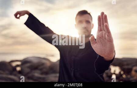 Fitness, karate o uomo in natura allenano il suo corpo in una rilassante meditazione zen con focus o calma energia marina. Chakra, mani o arti marziali sane Foto Stock