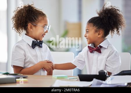 Piacere fare affari con voi. due adorabili bambine vestite come uomini d'affari seduti in ufficio e scuotendo le mani. Foto Stock