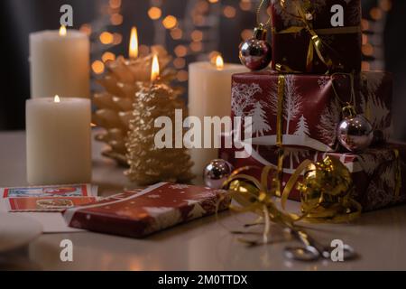 i regali confezionati con foto sono in fila e le candele accese sono in piedi sul tavolo Foto Stock
