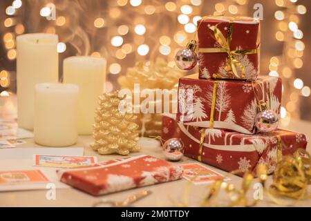 foto di candele accese e regali avvolti in carta rossa con luci sfocate sullo sfondo. la foto viene fatta con un tasto alto Foto Stock