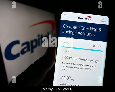 Persona che tiene il cellulare con il sito web della società americana Capital One Financial Corporation sullo schermo con il logo. Messa a fuoco al centro del display del telefono. Foto Stock