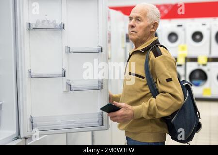 senor uomo pensionato acquistare frigorifero in showroom di elettrodomestici negozio Foto Stock