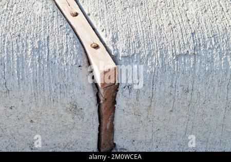 Giunti di dilatazione con distanziatori in legno che separano le sezioni in calcestruzzo di un cordolo per assorbire le sollecitazioni derivanti dall'espansione indotta dal calore. Immagine di primo piano a livello del suolo. Foto Stock