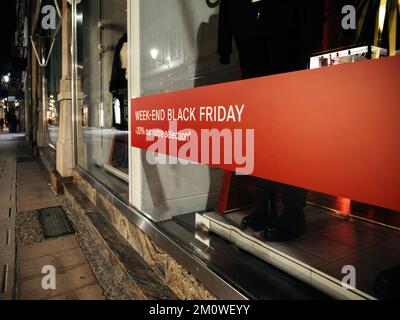 Week-end vendita Black Friday con testo tradotto dal francese meno il 20% sulle nostre selezioni di abbigliamento - vetrina di moda grande finestra con manichini Foto Stock