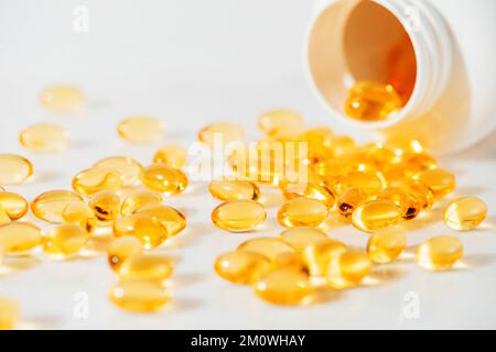 Olio di pesce Omega 3 versando dalla bottiglia contro lo sfondo di marmo bianco shot studio di alta qualità, concetto di mangiare sano, prendendo integratori Foto Stock