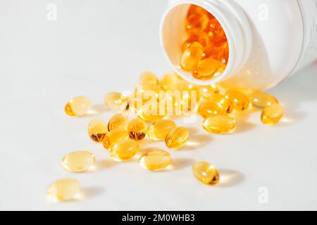 Olio di pesce Omega 3 versando dalla bottiglia contro lo sfondo di marmo bianco shot studio di alta qualità, concetto di mangiare sano, prendendo integratori Foto Stock