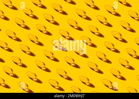 Pop Art Pattern Pesce capsule di olio con ripetizione Omega-3 su sfondo giallo studio shot, prendendo integratori alimentari e vitamine. Foto Stock