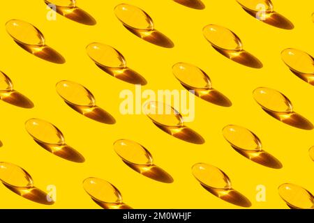 Pop Art Pattern Pesce capsule di olio con ripetizione Omega-3 su sfondo giallo studio shot, prendendo integratori alimentari e vitamine. Foto Stock