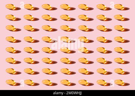 Modello di capsule di olio di pesce giallo con ripetizione Omega-3 su sfondo rosa studio shot, prendendo integratori alimentari e vitamine. Foto Stock