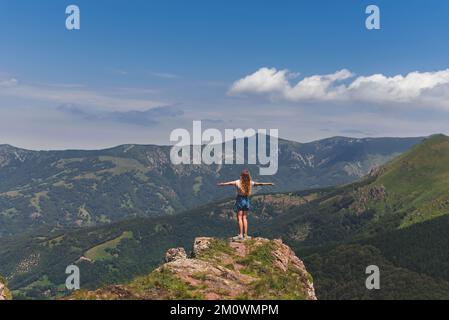 Donna con armi aperte sul bordo del picco della montagna Foto Stock