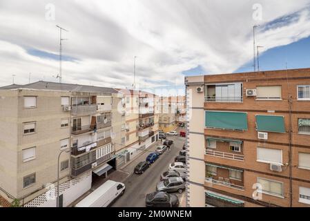 Vista su un edificio con alberi frondosi sulla facciata da una terrazza con una ringhiera di metallo verde Foto Stock