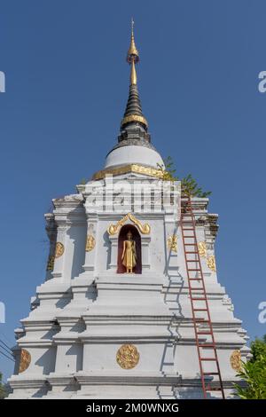 Vista panoramica dell'antico stupa bianco o chedi con statua del Buddha in piedi in nicchia presso lo storico tempio buddista Wat Chai Sri Phum, Chiang mai, Thailandia Foto Stock