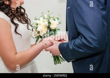 La sposa e lo sposo si sono messi sugli anelli di nozze dell'altro. Foto Stock