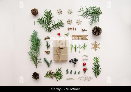 Composizione di Natale. Regalo, abete, pino, rami di cipresso e coni, decorazioni su sfondo bianco. Natale, inverno, Capodanno concetto. Foto Stock