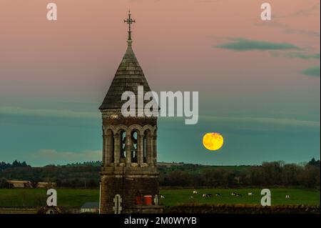 Timoleague, West Cork, Irlanda. 8th Dec, 2022. La luna piena sorge questa sera sulla Chiesa della Natività della Beata Vergine Maria a Timoleague. Viene dopo una giornata di temperature molto fredde, con incontrato Éireann avvertimento stasera potrebbe vedere bassi di -5C. Credit: AG News/Alamy Live News Foto Stock