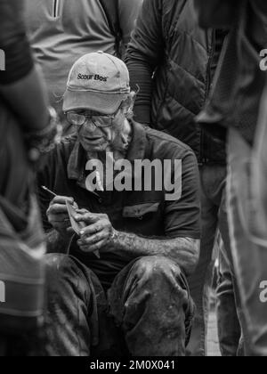 Un fuoco selettivo di un uomo che siede e che scrive su un foglio di carta Foto Stock