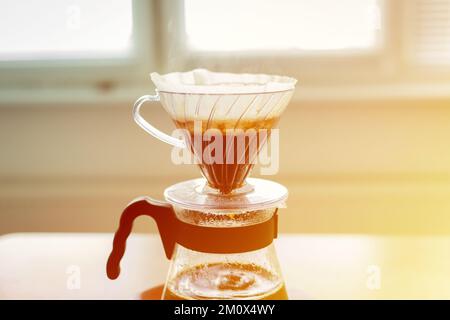 Primo piano di un V60 decanter, metodo alternativo di preparazione del caffè. Bolle d'aria sul letto del caffè. Foto Stock