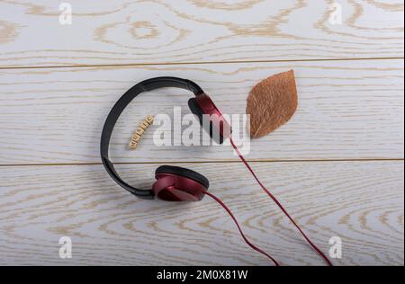 Dice-dimensioni cubetti di alfabeto musica ortografia, foglie secche e cuffie rosso su sfondo di legno Foto Stock