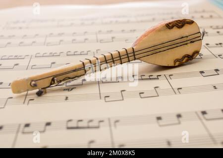 Modello di strumento musicale turco saz su carta con note musicali Foto Stock