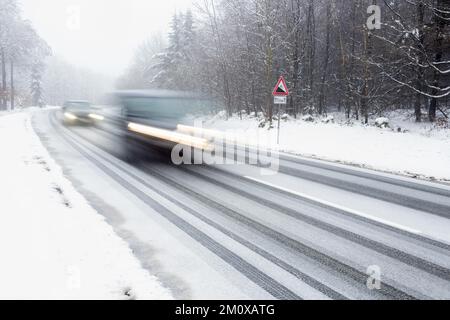 Due vetture che guidano su strade innevate, sfocatura del movimento, segnale di avvertimento in discesa, Assia, Germania, Europa Foto Stock