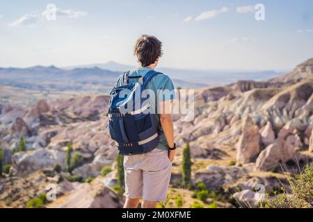 Giovane esploratore valle con formazioni rocciose e grotte delle fate vicino a Goreme in Cappadocia Turchia Foto Stock