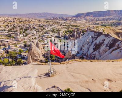 Bandiera turca sulla collina con tipiche formazioni rocciose di tufo della Cappadocia sullo sfondo di un cielo blu, Goreme, Turchia Foto Stock