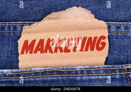 Affari e finanza. Una scatola di cartone con l'iscrizione-MARKETING si stacca da jeans. Foto Stock