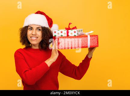 Donna afro-americana felice tiene in mano stack di regali di natale. sorridente. Natale Foto Stock