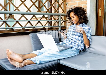 giovane donna che lavora a casa, studentessa afroamericana che utilizza la tecnologia per preparare gli esami, donna con vitiligine che si rilassa in terrazza Foto Stock