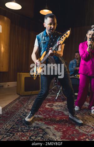 Un energico chitarrista uomo che suona con una band musicale in uno studio. Foto di alta qualità Foto Stock