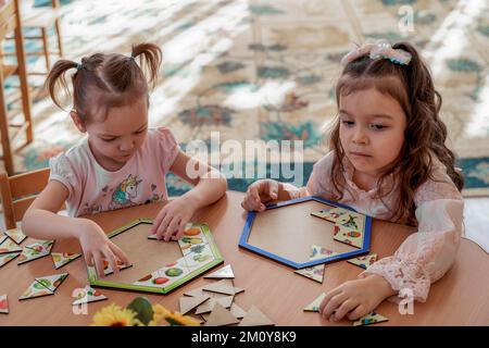 due ragazze raccogliere puzzle al tavolo Foto Stock