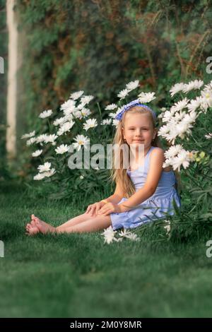 ragazza seduta in un prato tra fiori bianchi Foto Stock