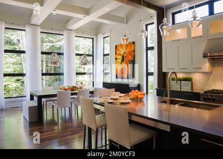 Isola e tavolo da pranzo in opulenta cucina open concept sala da pranzo all'interno di una casa di lusso. Foto Stock