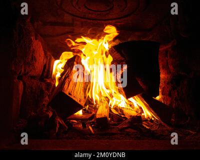 legno aranciato in un forno in pietra all'interno, fuoco nel camino. Foto Stock