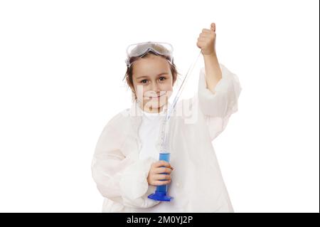 Adorabile bambina gocciola poche gocce di reagente da pipetta graduata in un cilindro di misurazione in una lezione di chimica Foto Stock