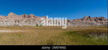 Vista panoramica di una cresta di cime colorate sopra una prateria erbosa nel Badlands National Park, South Dakota Foto Stock