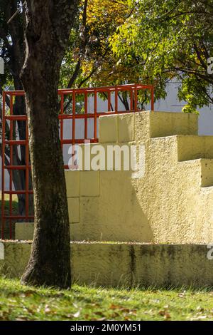 Colorato parco giochi per bambini attività nel parco pubblico circondato da alberi verdi al tramonto Foto Stock