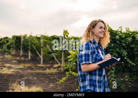 Donna agronomo specialista in possesso di un blocco note che controlla la qualità dei vigneti. Spazio di copia. Concetto di raccolto. Concetto di business ecologico. Business Foto Stock