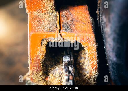 Catena della motosega sul primo piano dello pneumatico. Denti di sega per il taglio del legno su uno sfondo sfocato. Attrezzo agricolo Foto Stock