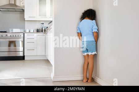 Questo non è divertente. una bambina in piedi nell'angolo a casa. Foto Stock