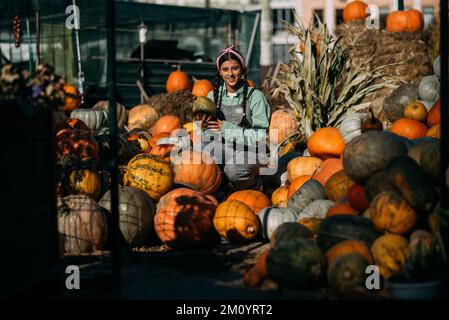 La donna contadina in una tuta di denim sceglie la zucca matura Foto Stock