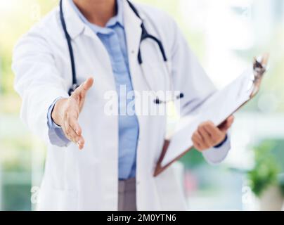 Non avete niente di cui preoccuparsi. Primo piano di un medico irriconoscibile che estende una stretta di mano in un ospedale. Foto Stock