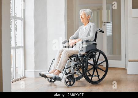 Theres ancora così tanta speranza per il mio futuro. una donna anziana seduta su una sedia a rotelle e guardando pensieroso fuori dalla finestra a casa. Foto Stock