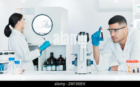 Preparazione di un nuovo campione. un giovane scienziato che analizza i campioni mentre lavora in laboratorio con un collega in background. Foto Stock