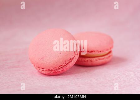 Due macaroni di colore rosa primo piano, dolce cucina francese, fondo pastello tenue Foto Stock