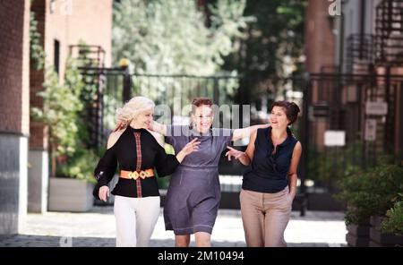 Donne mature sorridenti. Felice gruppo di amici di mezza età che camminano insieme città strada, abbracciando e ridendo. Amicizia donna anziana Foto Stock