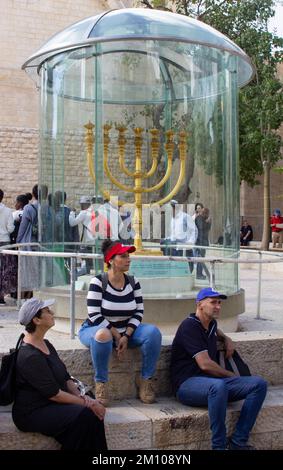 9 novembre 2022 il menorah d'oro solido è stato fissato in un caso a prova di proiettile in mostra nella piazza acciottolata del quartiere ebraico a Gerusalemme. I visitatori si riposano Foto Stock